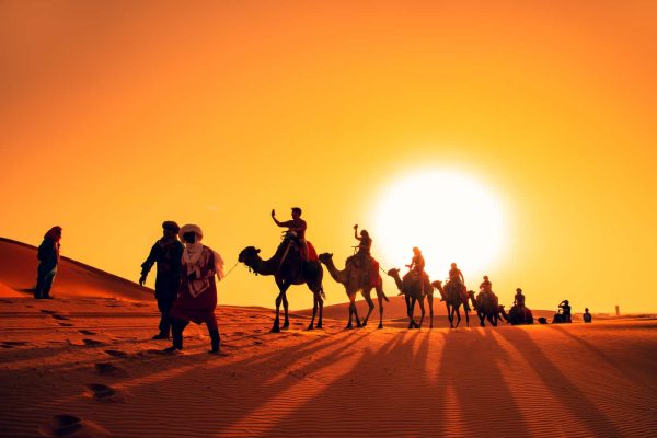 Camel caravan at sunset in the Sahara desert. Erg Chebbi, Merzouga,  Morocco - September 15, 2019.